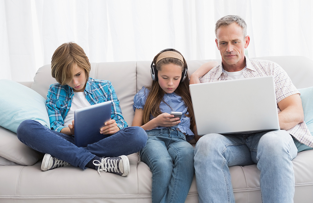 family on couch with laptops and phones